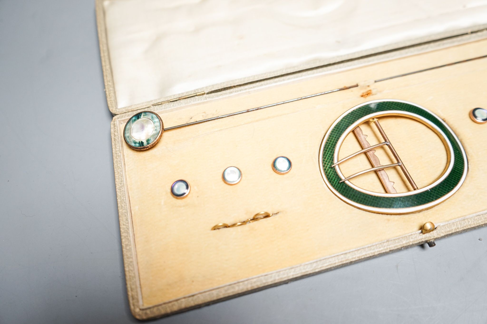 An early 20th century cased gilt metal and enamel buckle, buttons and hat pin set, case 30cm